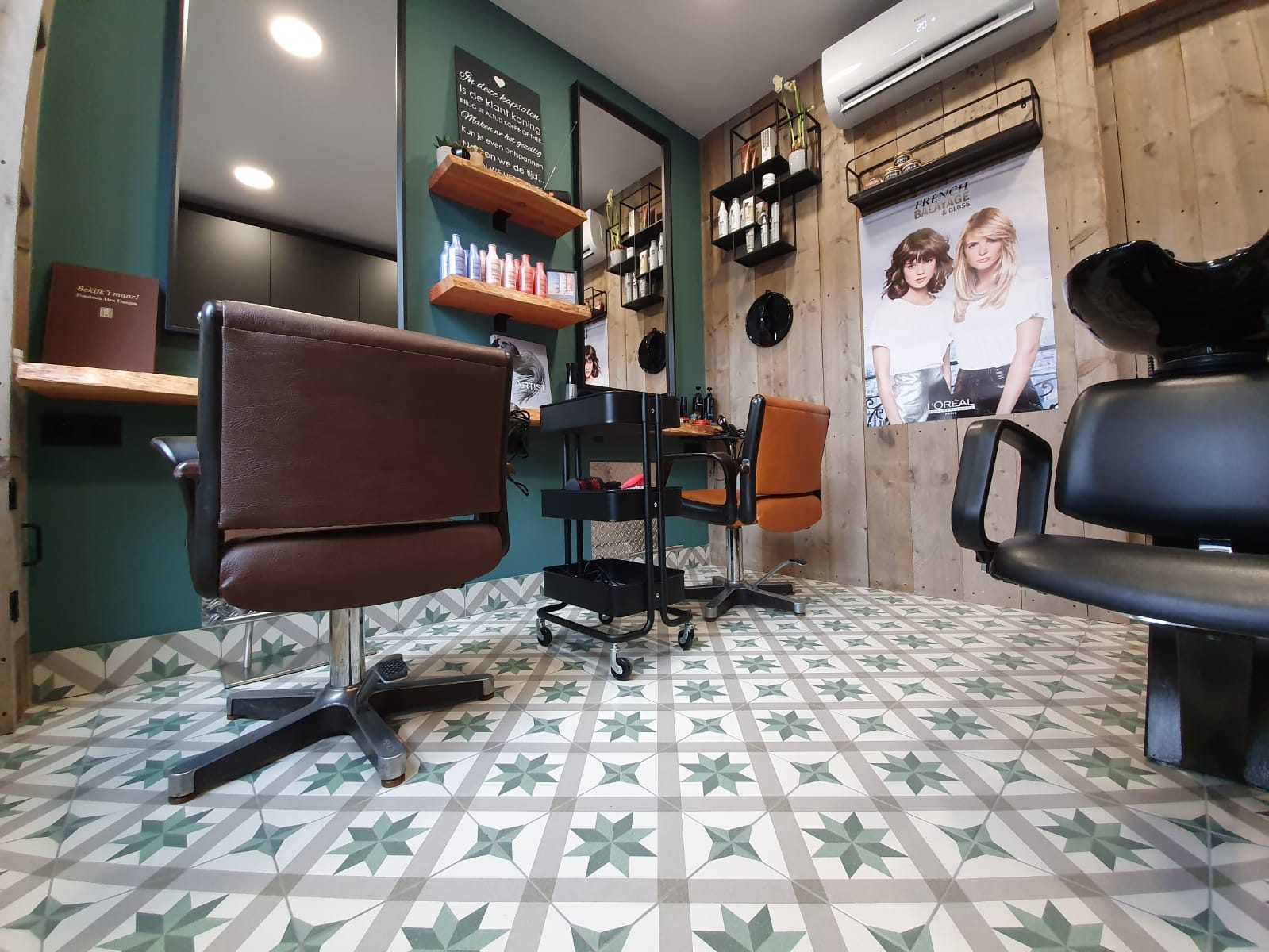 De salon met groene tegelvloer en kappersstoelen