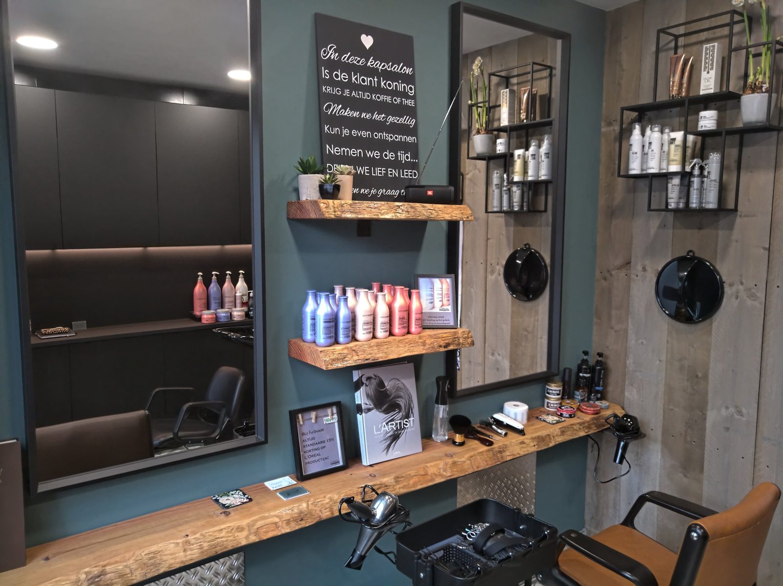 De salon van HetHair: groene muur, houten planken en spiegels